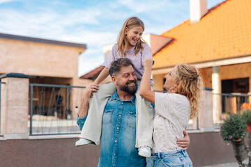 Happy family is having fun outdoors in front of their house