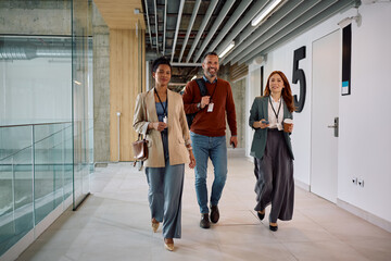 Obraz premium Happy business team walking through office hallway.
