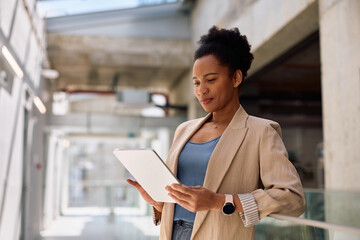 Smiling black businesswoman working on digital tablet in office.