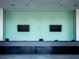 Modern reception or registration desk with two wall-mounted screens and electronic devices for check-in or control in a secure facility – Customs. Reception.