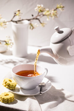 Tea poured into white cup and saucer with spring branches