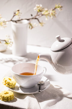 Tea poured into white cup and saucer with spring branches