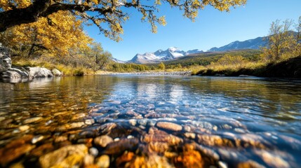 Obraz premium A tranquil river reflects the stunning autumn foliage and majestic mountains in this picturesque landscape, capturing the beauty of nature's seasonal transformation.