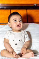 baby sitting in bed screaming to be seen