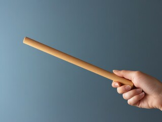 A hand holding a smooth wooden dowel, isolated to highlight its simple craftsmanship