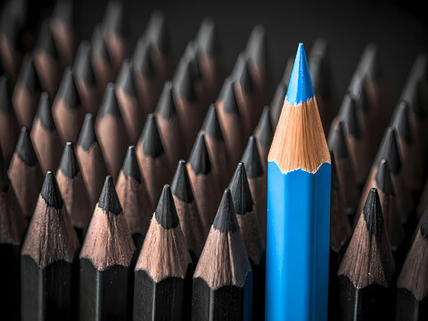 Blue pencil standing out from the crowd of black pencils