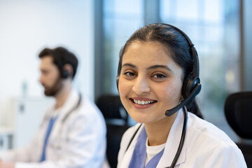 A friendly healthcare professional smiles at the camera while working, wearing a headset in a...