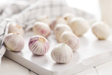 Solo glove garlic bulbs on white table.