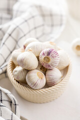 Solo glove garlic bulbs in bowl on white table.