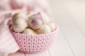 Solo glove garlic bulbs in bowl on white table.