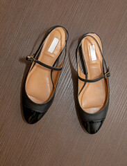 Black. leather Mary jane style shoes on wood background
