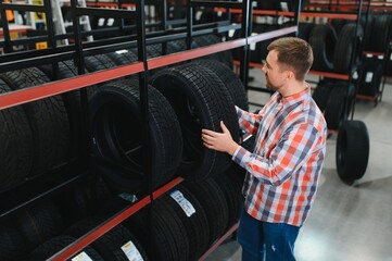 Portrait young man customer examining brand and product characteristics while buying new tires in...