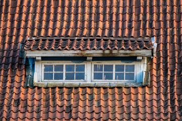 Dormer Window on a Red Tiled Roof. Old Window on a Rustic Red Tile Roof