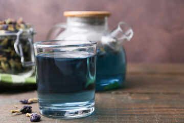 Delicious butterfly pea flower tea on wooden table against brown background. Space for text