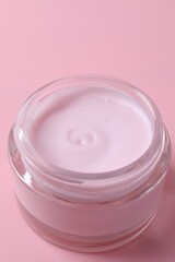 Jar of moisturizing cream on pink background, closeup