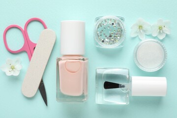 Naklejka premium Set of different manicure tools and flowers on turquoise background, flat lay