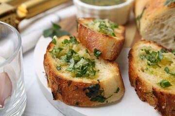 Tasty bread with garlic, herbs and oil on white table, closeup