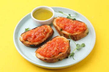 Tasty bread with tomato, microgreens and oil on yellow background, closeup
