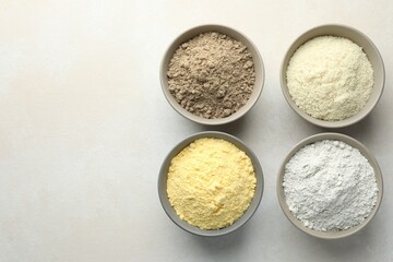 Different types of flour in bowls on light grey table, flat lay. Space for text