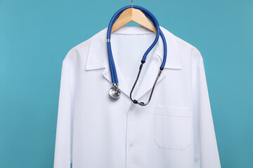 Doctor's coat with stethoscope on hanger against blue background
