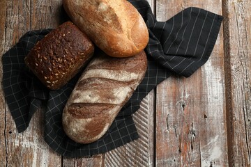 Different types of fresh bread on wooden table, flat lay. Space for text
