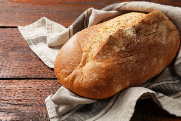 Fresh loaf of bread on wooden table, closeup. Space for text