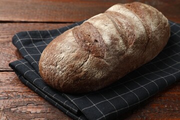 Fresh loaf of bread on wooden table, closeup