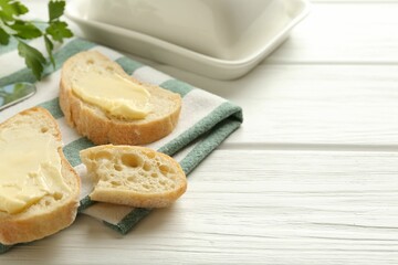 Slices of bread with butter on white wooden table, closeup. Space for text
