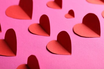 Many paper hearts on magenta color background, closeup
