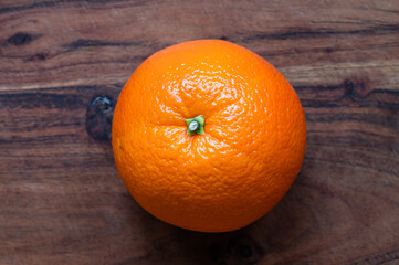 Top view of a whole orange on a wood cutting board