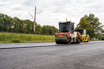 Two Heavy Asphalt Road Roller with heavy vibration roller compactor that press new hot asphalt on the roadway on a road construction.
