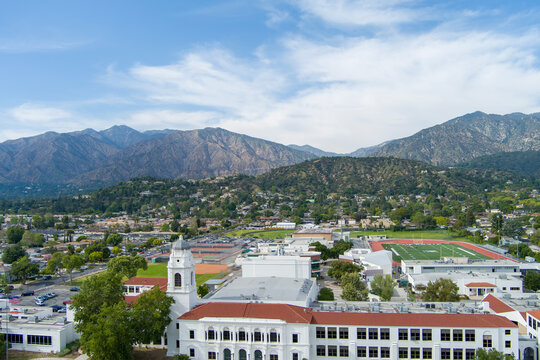 aerial footage of Monrovia High school with majestic mountain ranges, homes and lush green trees in Monrovia California USA