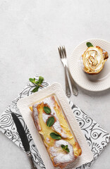 Finnish pancake in the roll cake with cream on white plate ant cut piece near on light background with copy space, top vertical view