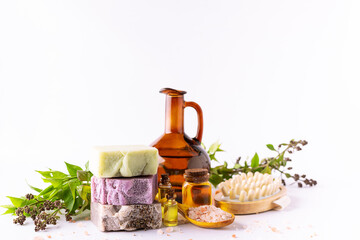 Bright composition with set of natural eco spa and wellness products such as handmade soap, essential oils, Himalaya salt, massage brushes and fresh green twigs on white background, selective focus.