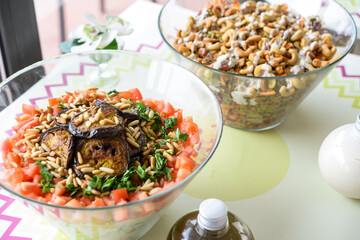 Assorted Salads in Glass Bowls include grains, vegetables, and nuts served on a table with dressing bottles closeup side view