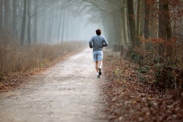 Fototapeta premium Jogger on a Foggy Forest Trail: Solitude, Fitness, and Natural Beauty in a Serene Landscape