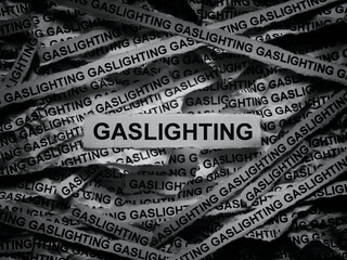 Strips of newspaper with the words Gaslighting typed on them. Black and white.