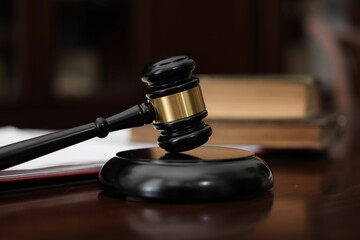 Judge workplace with gavel and books indoors, closeup
