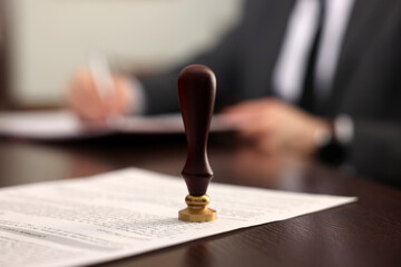 Fototapeta premium Notary working at wooden table in office, focus on stamp