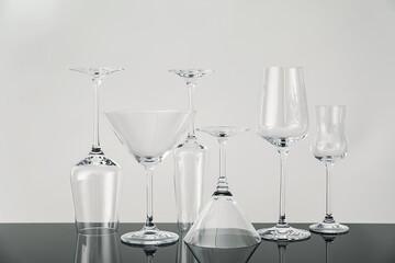 Many empty clean glasses on mirror surface against grey background