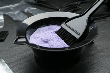 Bleaching powder and hairdresser's tools on black table, closeup