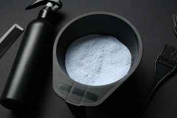 Bleaching powder and hairdresser's tools on black background, closeup