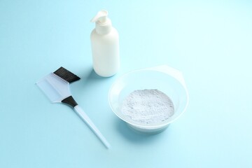 Bleaching powder and hairdresser's tools on light blue background