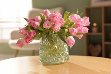 Beautiful tulips in vase on wooden table indoors, closeup