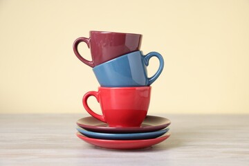 Beautiful cups and saucers on light wooden table against beige background