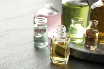 Open perfume bottles with aromatic essential oils on dark textured table, closeup