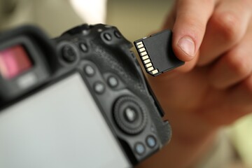 Man inserting SD memory card into photo camera, closeup