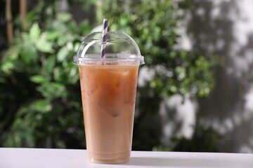 Tasty iced coffee on white table against blurred background