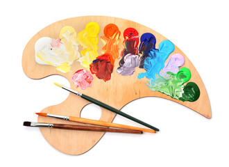 Wooden palette with paints and brushes isolated on white, top view