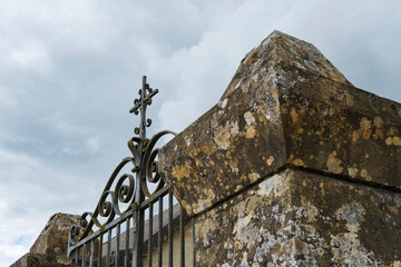 Old iron cemetery gate against an ominous sky with clouds in Cornac Lot Occitanie in Southern France